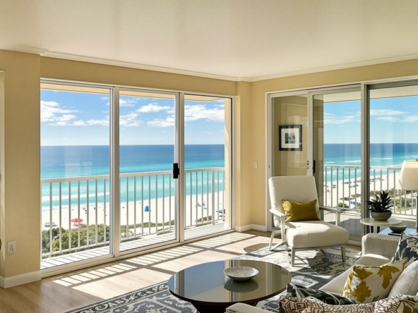 Oceanfront condo with balcony overlooking turquoise water and beach.