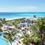 Luxurious waterfront mansion with ocean view and palm trees.