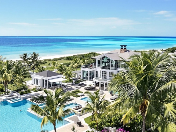 Luxurious waterfront mansion with ocean view and palm trees.